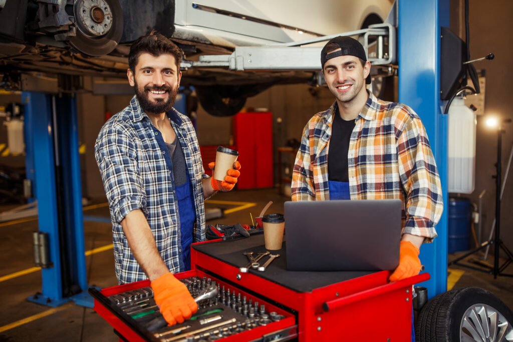 portrait two smiling specialists working laptop computer looking front modern service center | Roberts Mobile Mechanics