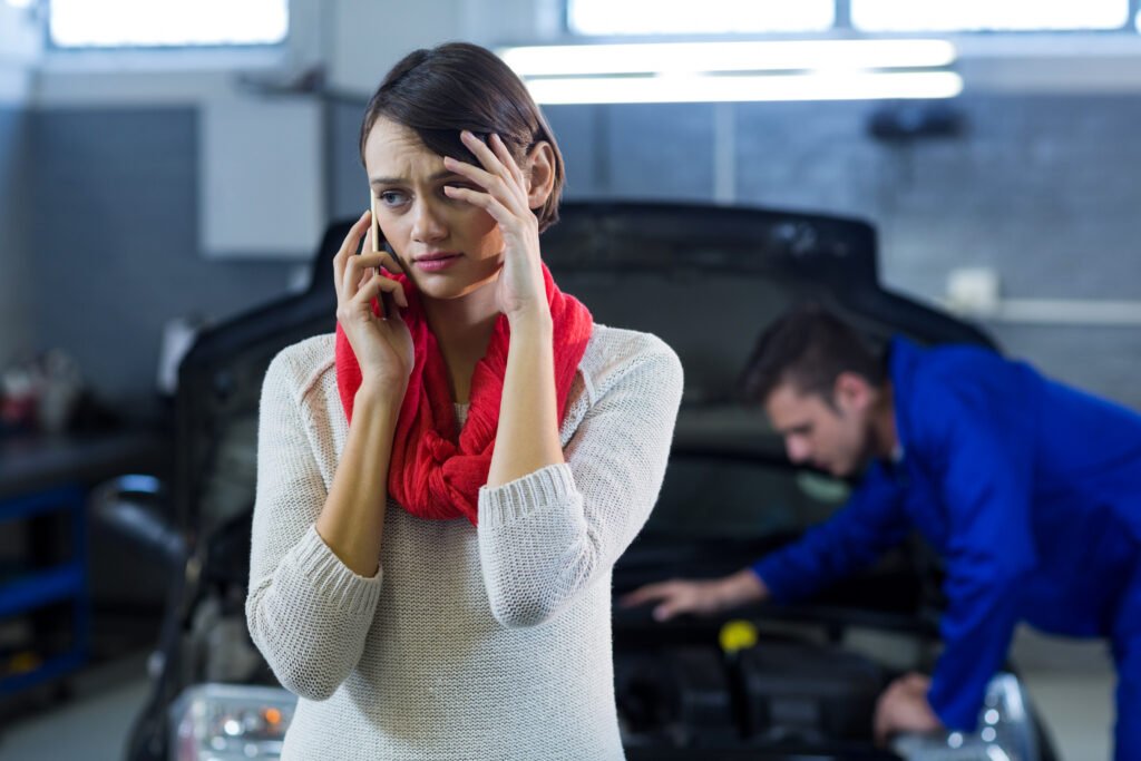 worried customer talking mobile phone while mechanic examining car background | Roberts Mobile Mechanics
