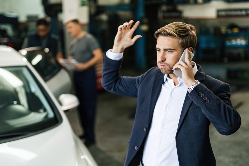 young displeased businessman talking phone while being car repair workshop | Roberts Mobile Mechanics