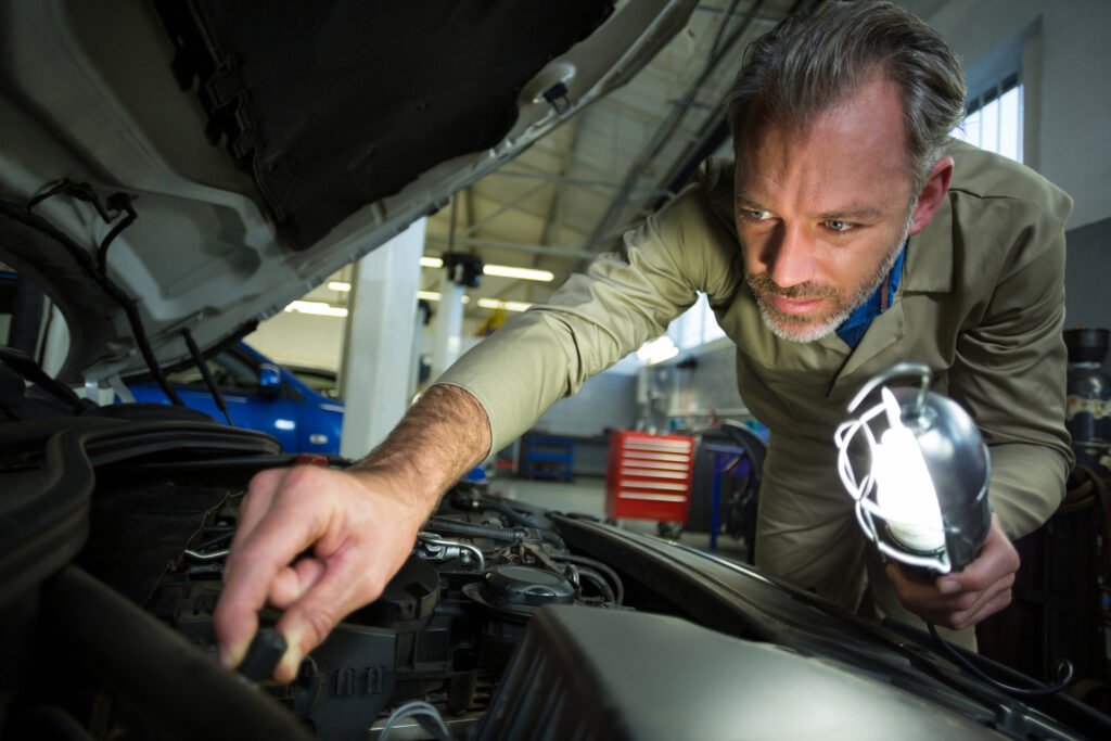 Mechanic examining a car with lamp in Nashville, TN | Roberts Mobile Mechanics