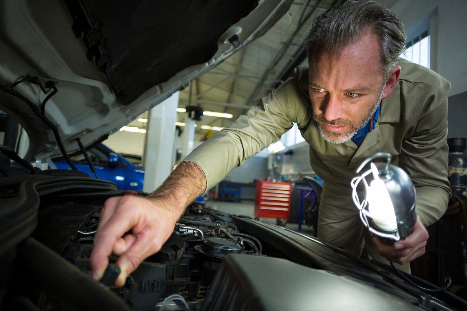 Mechanic examining a car with lamp in Nashville, TN | Roberts Mobile Mechanics