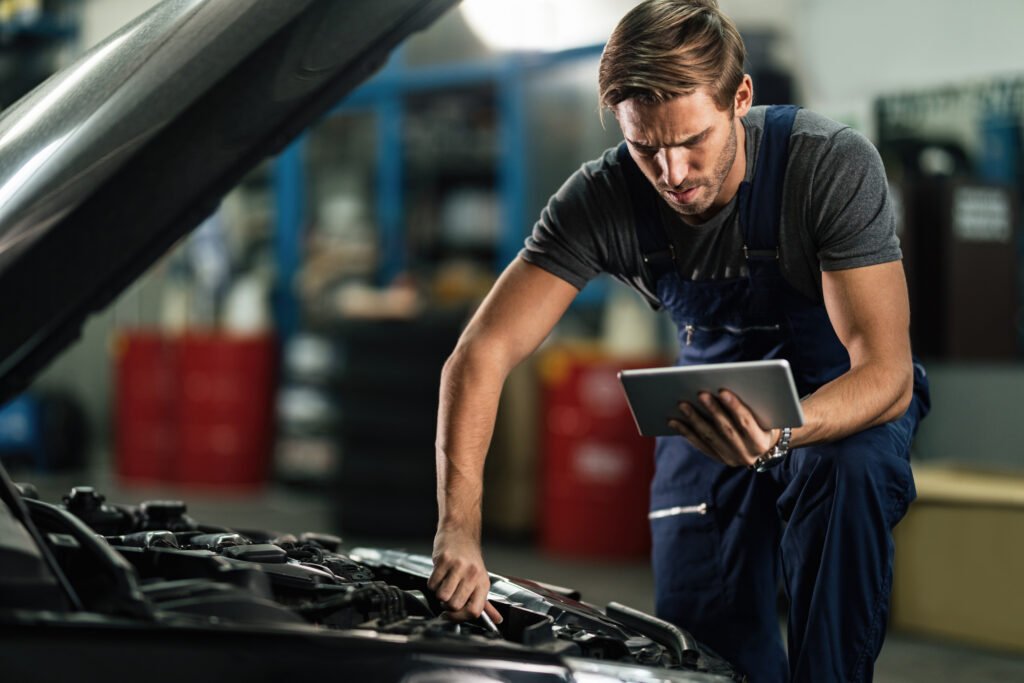 Young auto mechanic using touchpad while repairing car engine in Nashville, TN | Roberts Mobile Mechanics