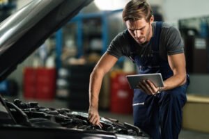 Blog | Roberts Mobile Mechanics Young auto mechanic using touchpad while repairing car engine in Nashville, TN | Roberts Mobile Mechanics